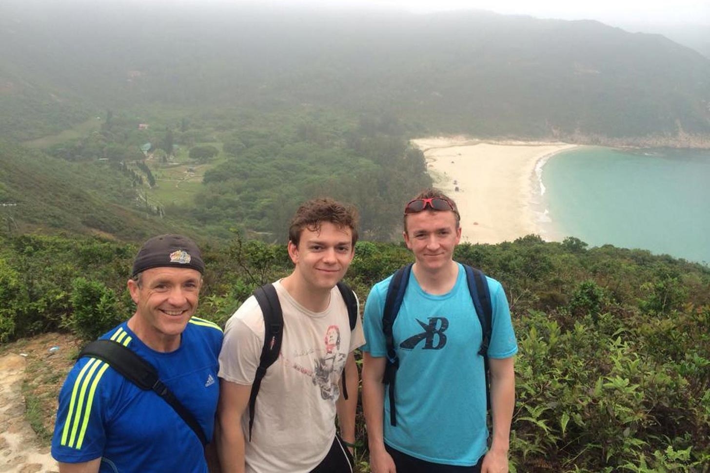 Liam (middle) with, his dad and brother, on a hike with one of Hong Kong's many beaches in the background. 