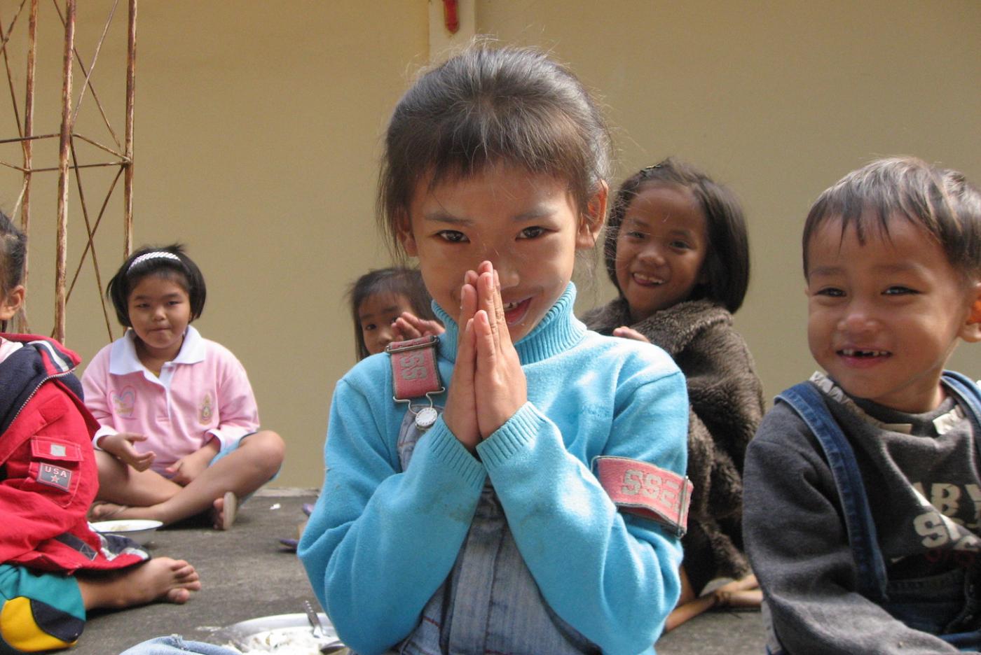 A girl demonstrates how to &quot;wai&quot; in Thailand. 